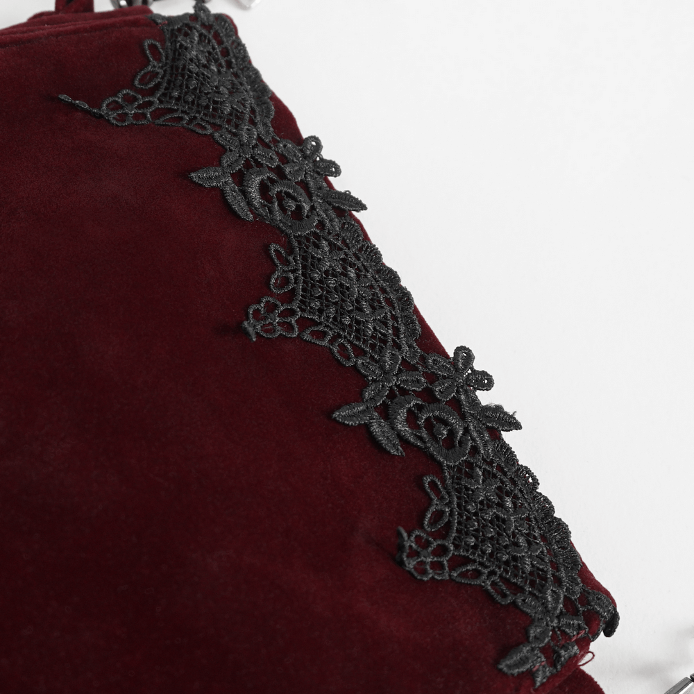 Close-up of luxurious red velvet shoulder bag with intricate black lace embroidery.