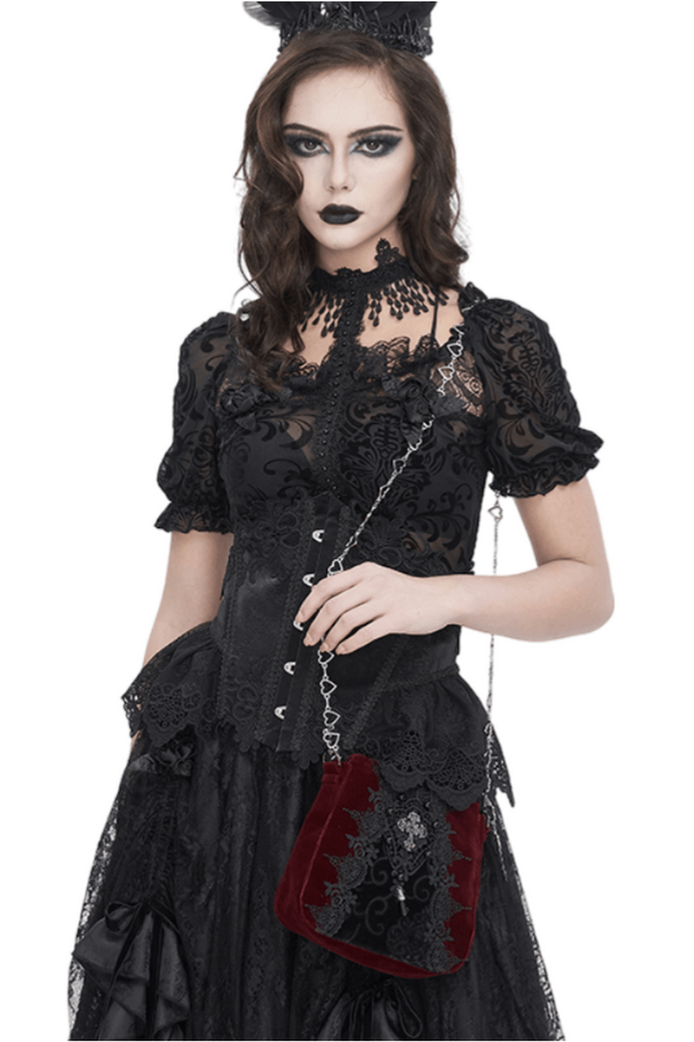 Gothic woman in black lace outfit holding a luxurious velvet shoulder bag with silver chain accents.