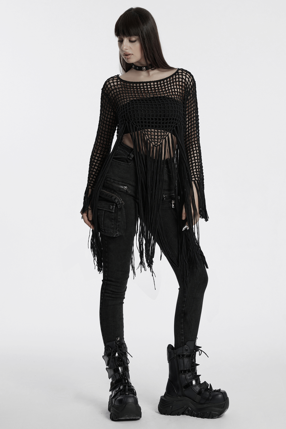 Edgy women's gothic tassel knit sweater with hollow design, paired with black skinny pants and chunky boots.