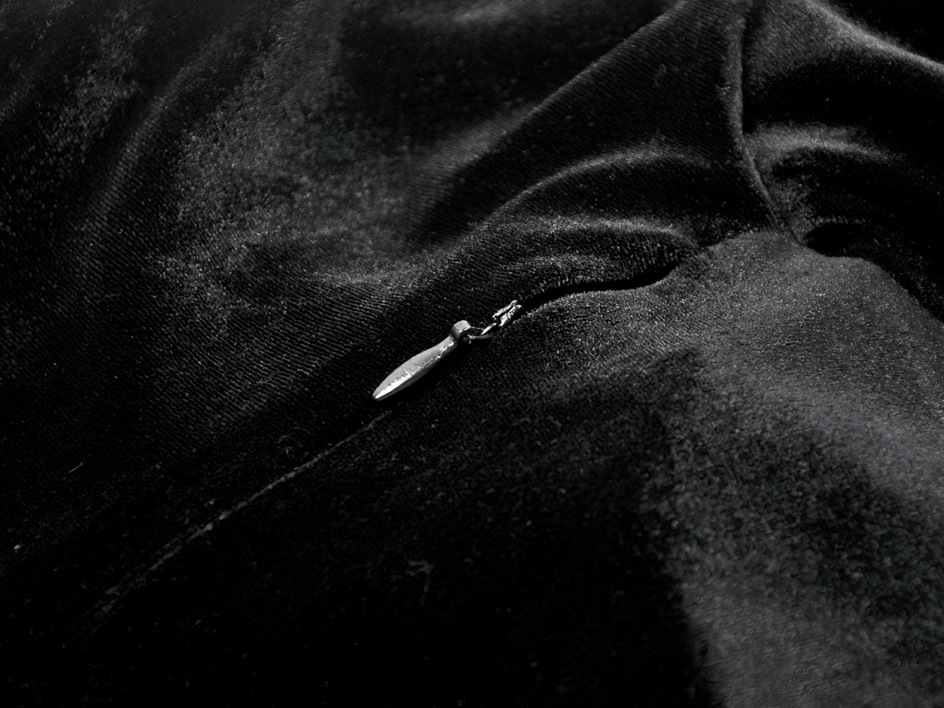 Close-up of the zipper on a Women's Gothic Velvet Maxi Dress with Lace Bell Sleeves against a black velvet fabric.