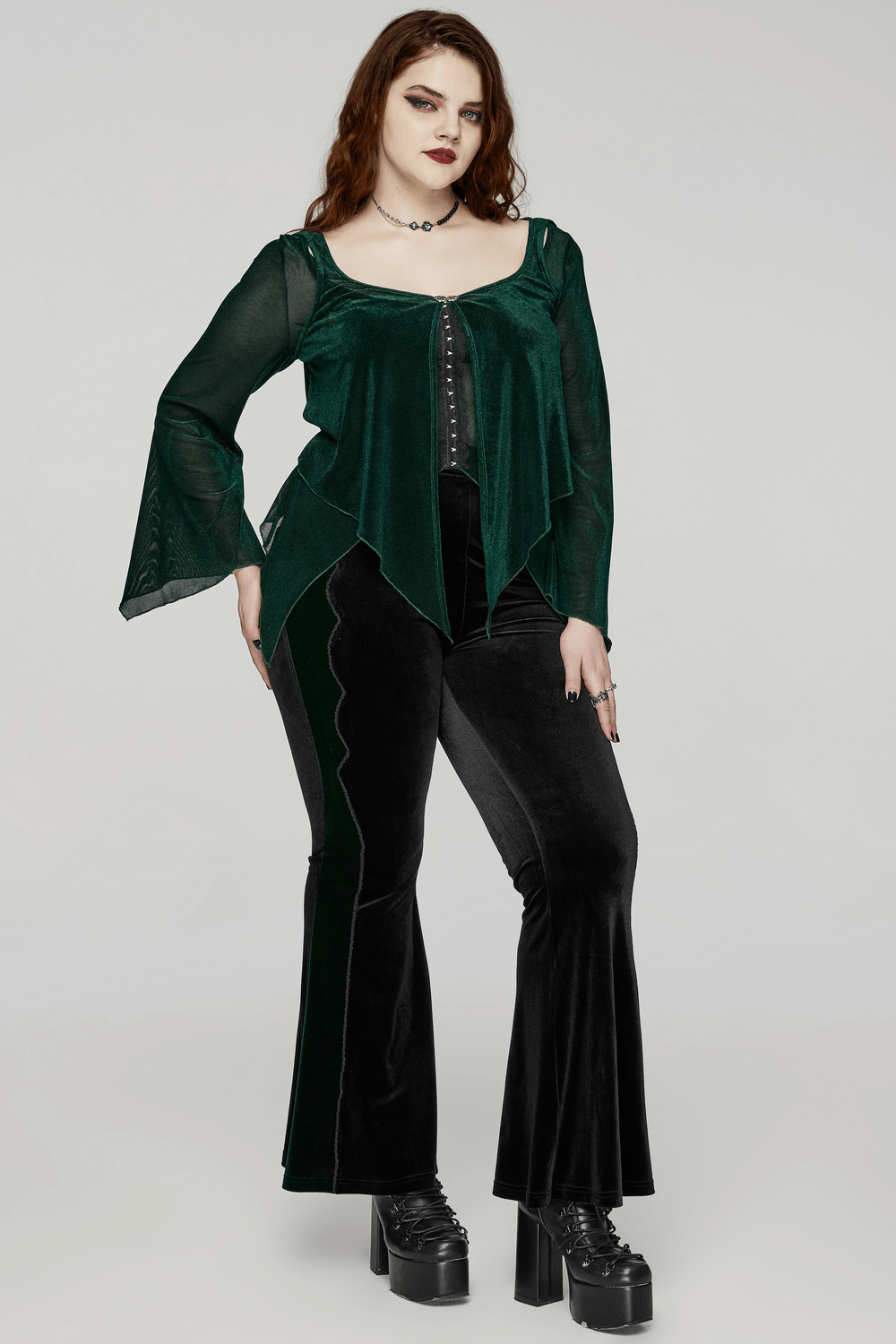 Chic women's green top with bell sleeves, hooks fastening, paired with black flared pants for a stylish look.