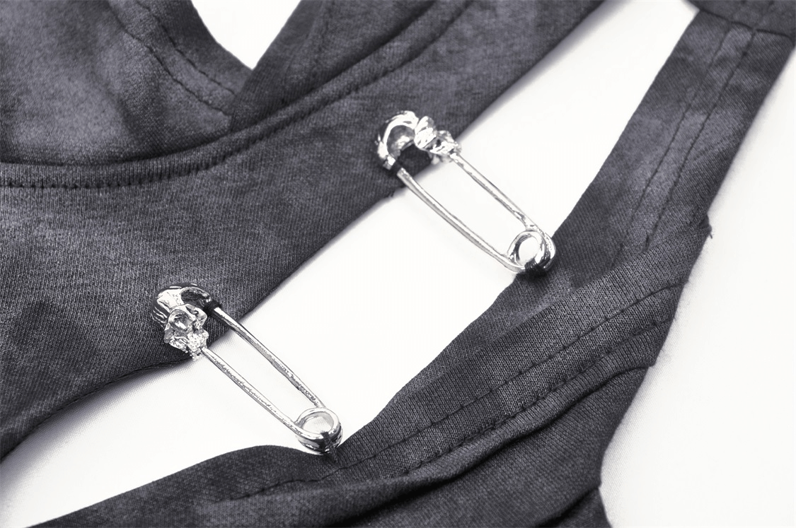 Close-up of metal pins on a black sleeveless punk top, showcasing edgy gothic style.