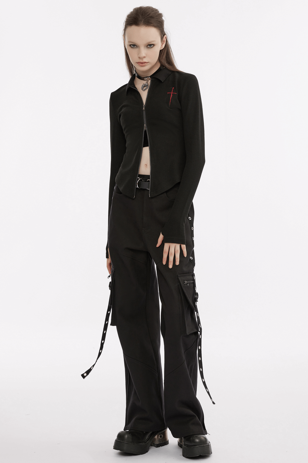 Women's black knitted zippered top with red cross embroidery, styled with edgy black cargo pants.
