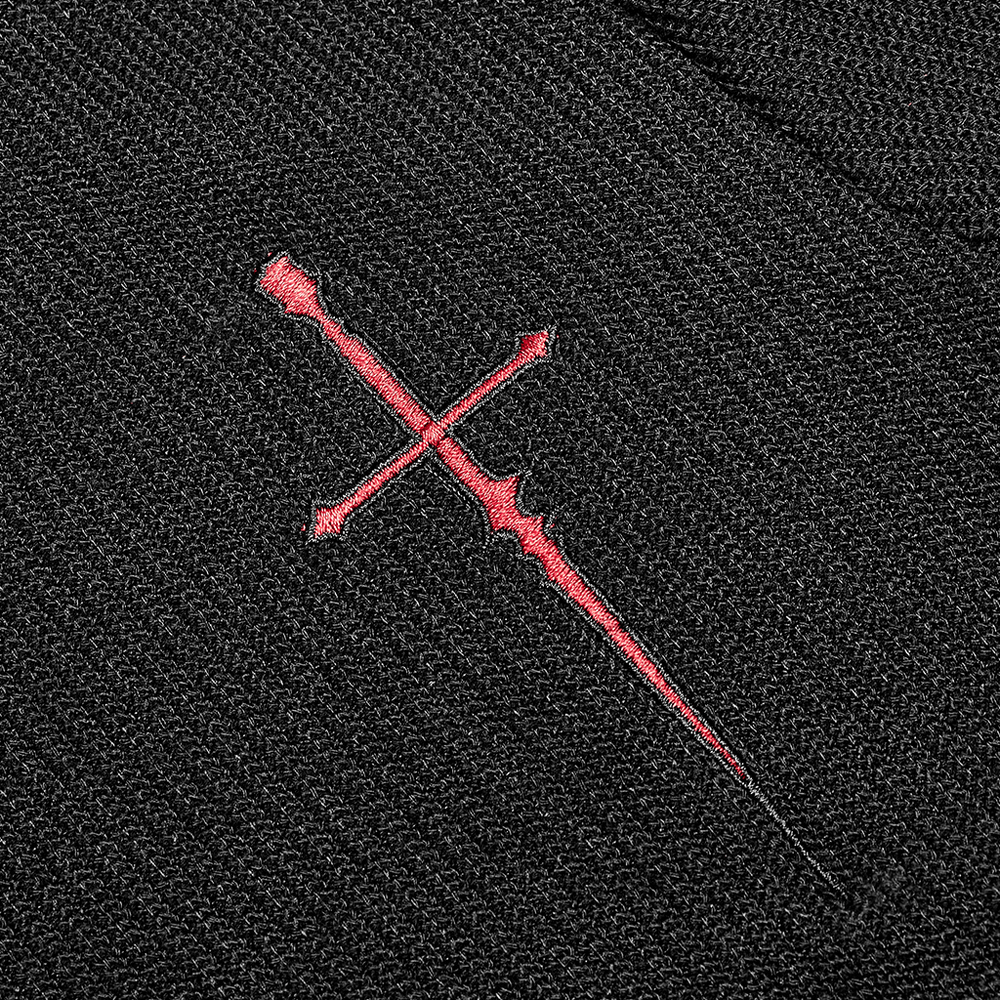 Close-up of red sword cross embroidery on black knitted fabric, showcasing edgy punk style.