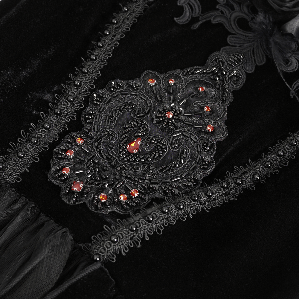 Close-up of intricate black lace detailing with red beads on a stylish evening dress.