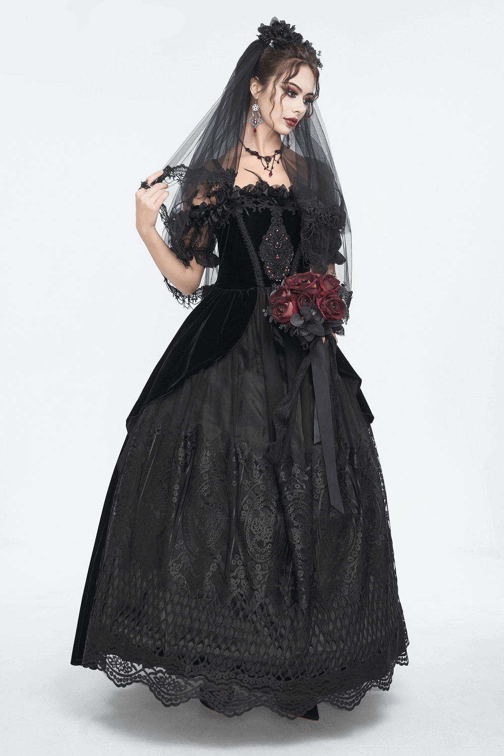 Elegant black lace evening gown with feather sleeves, complemented by a floral bouquet and intricate details.
