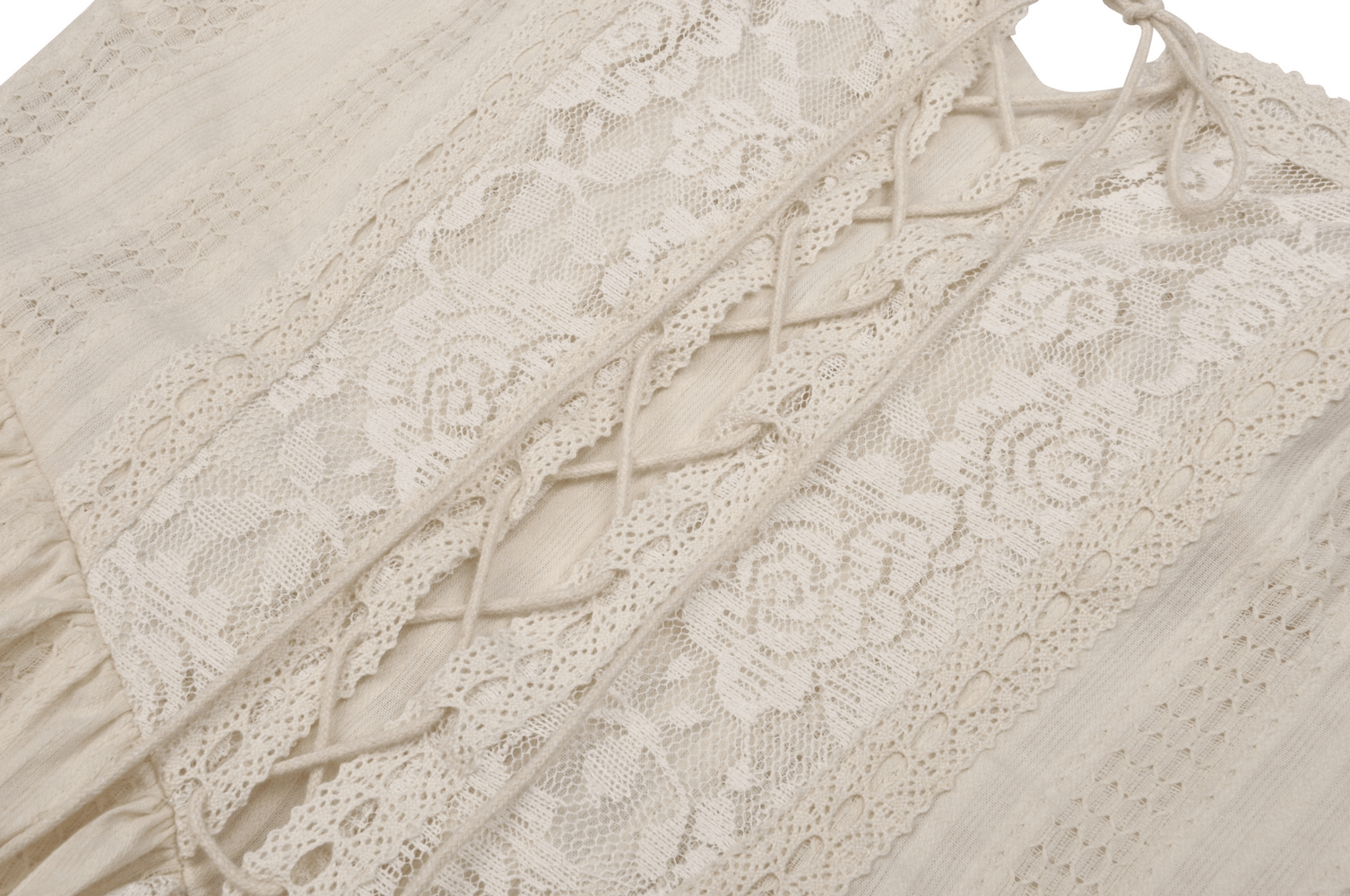 Detailed view of cream lace fabric with floral patterns and intricate lace-up design for women's mini dress.