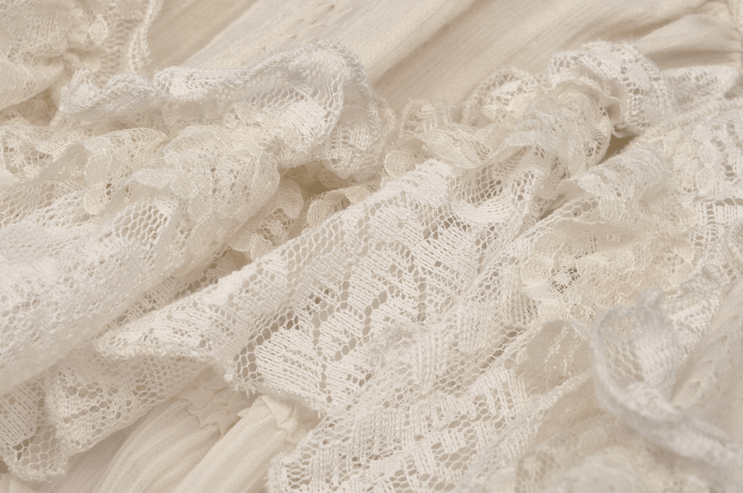 Close-up of delicate cream lace fabric with ruffled layers, perfect for a women's gothic mini dress.