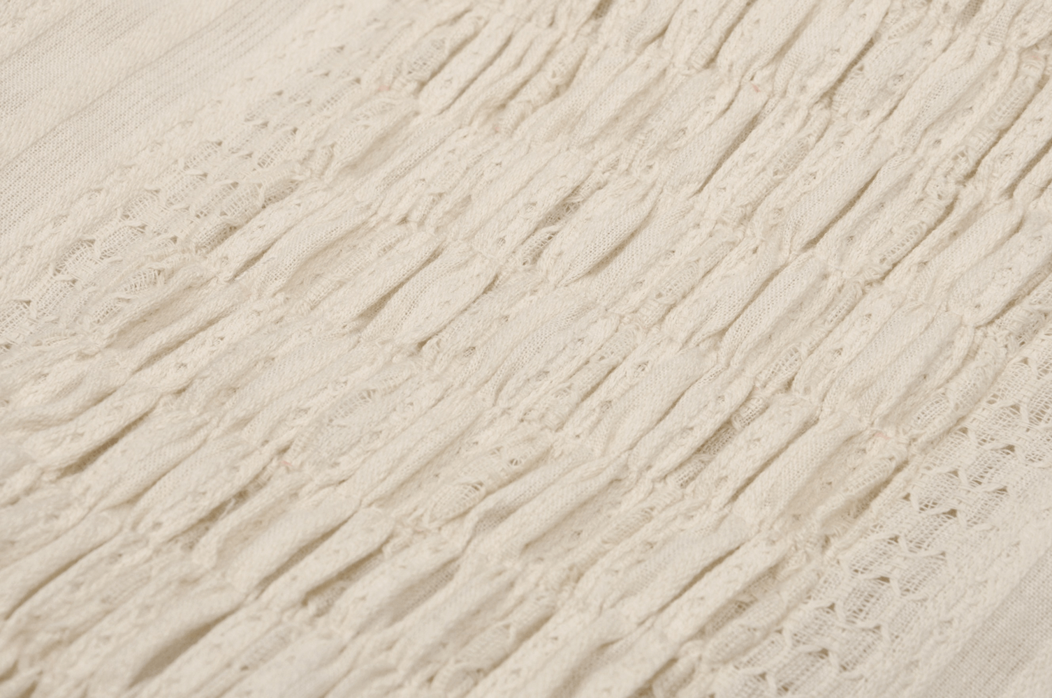 Close-up view of intricate cream lace fabric showcasing detailed textures and patterns.