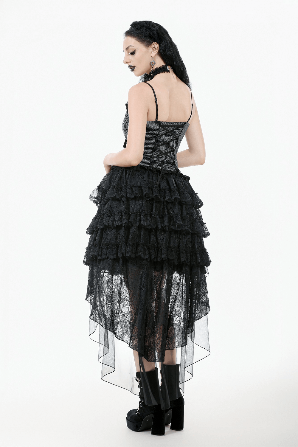 Back view of a woman in a Gothic lace ruffled high-low skirt, showcasing sheer layers and edgy black boots.