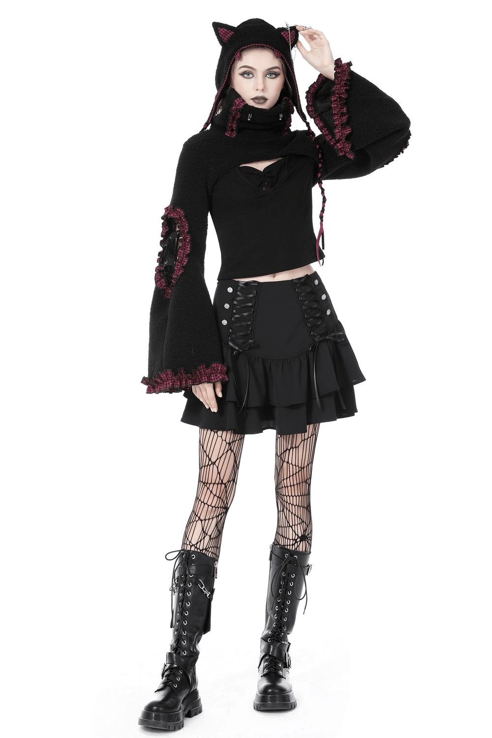 Gothic woman in layered mini skirt with lace-up accents, paired with a hooded top and fishnet tights.