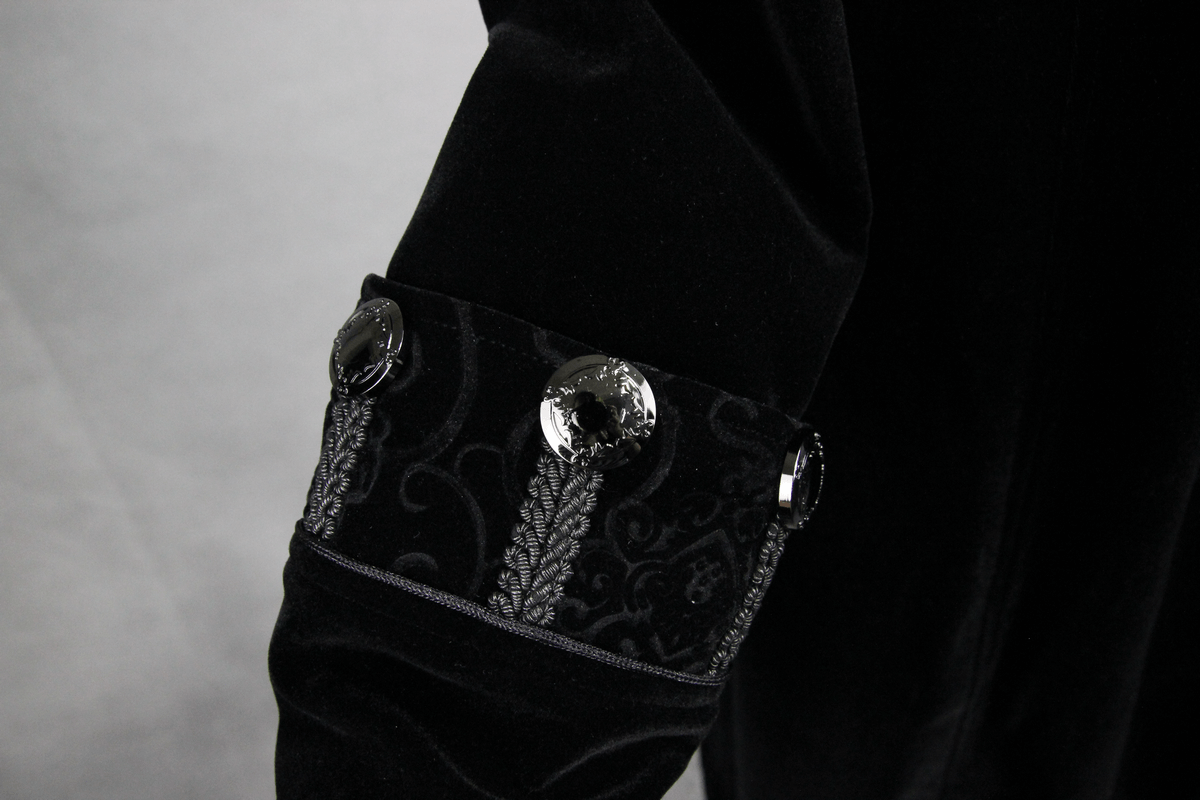 Close-up of the stylish cuff detail on a women's gothic black coat featuring elegant buttons and ornate jacquard fabric.