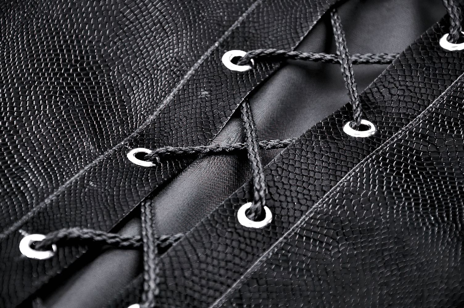 Close-up of black laces on a gothic-inspired cape, showcasing intricate detailing and silver eyelets.