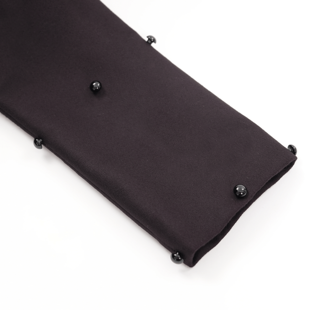 Close-up of a dark fabric sleeve with black bead accents, part of a gothic-inspired women's long coat.