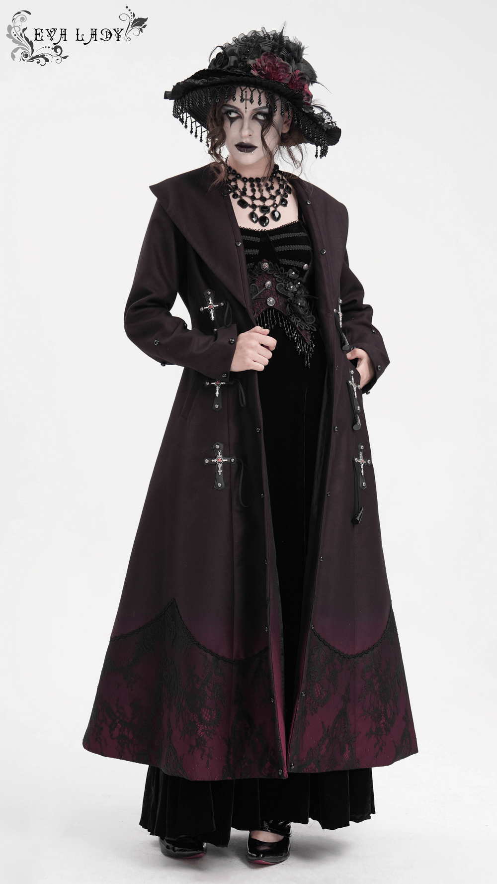 Gothic long coat with faux fur trim, silver cross buckles, and A-line silhouette, paired with a dark-themed outfit on a model.