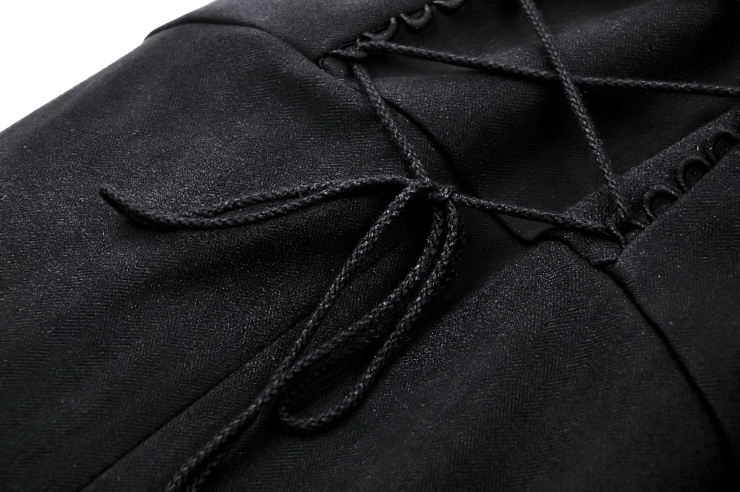 Close-up of black trench coat fabric with intricate lacing detail, showcasing luxury and elegance.
