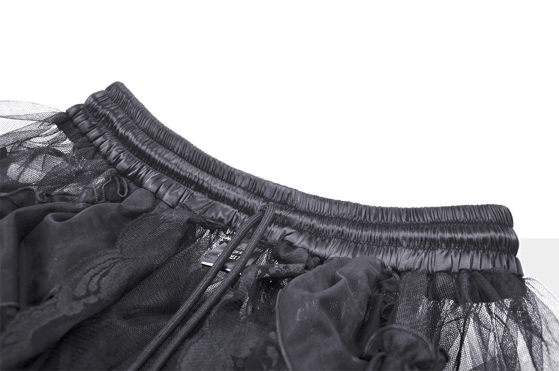 Close-up of the waistband of a black mesh gothic skirt with lace and ruffles, showcasing its delicate design and elastic fit.