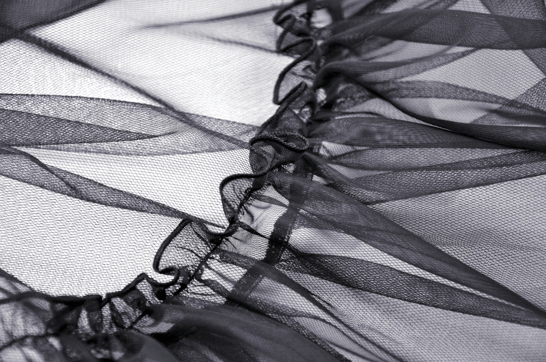 Close-up of airy black mesh fabric with delicate ruffles, perfect for a gothic high-low skirt design.