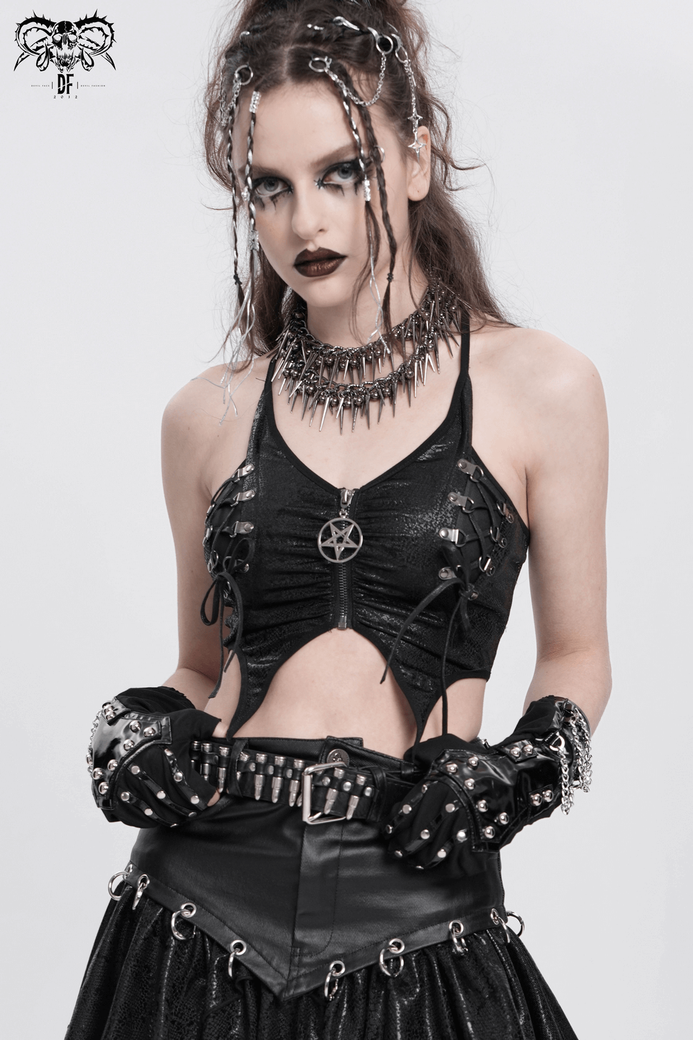 Edgy woman in black studded top and gloves, featuring chains and goth accessories for a striking fashion statement.