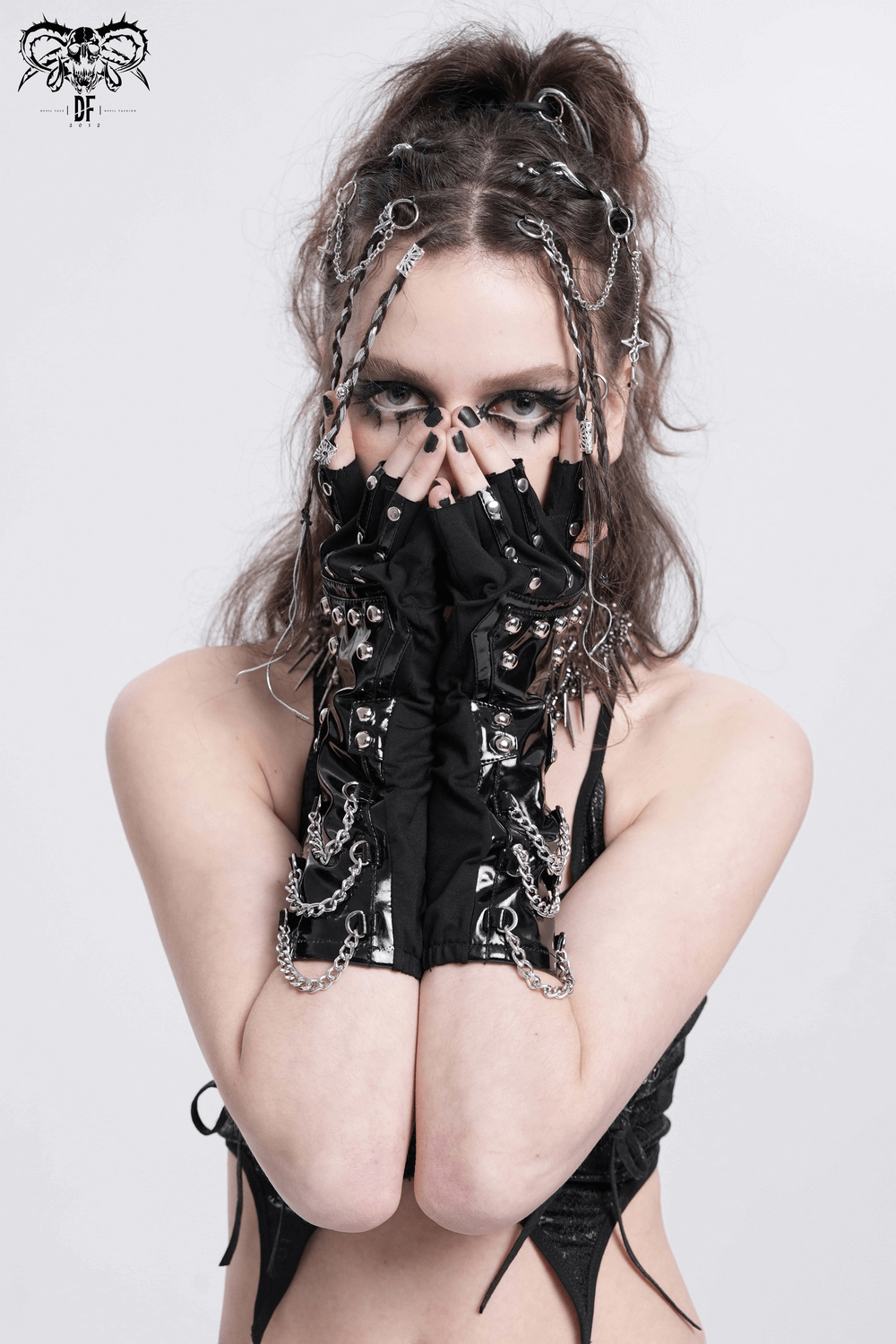 Edgy woman posing with black studded leather gloves and chains, showcasing a bold fashion statement.