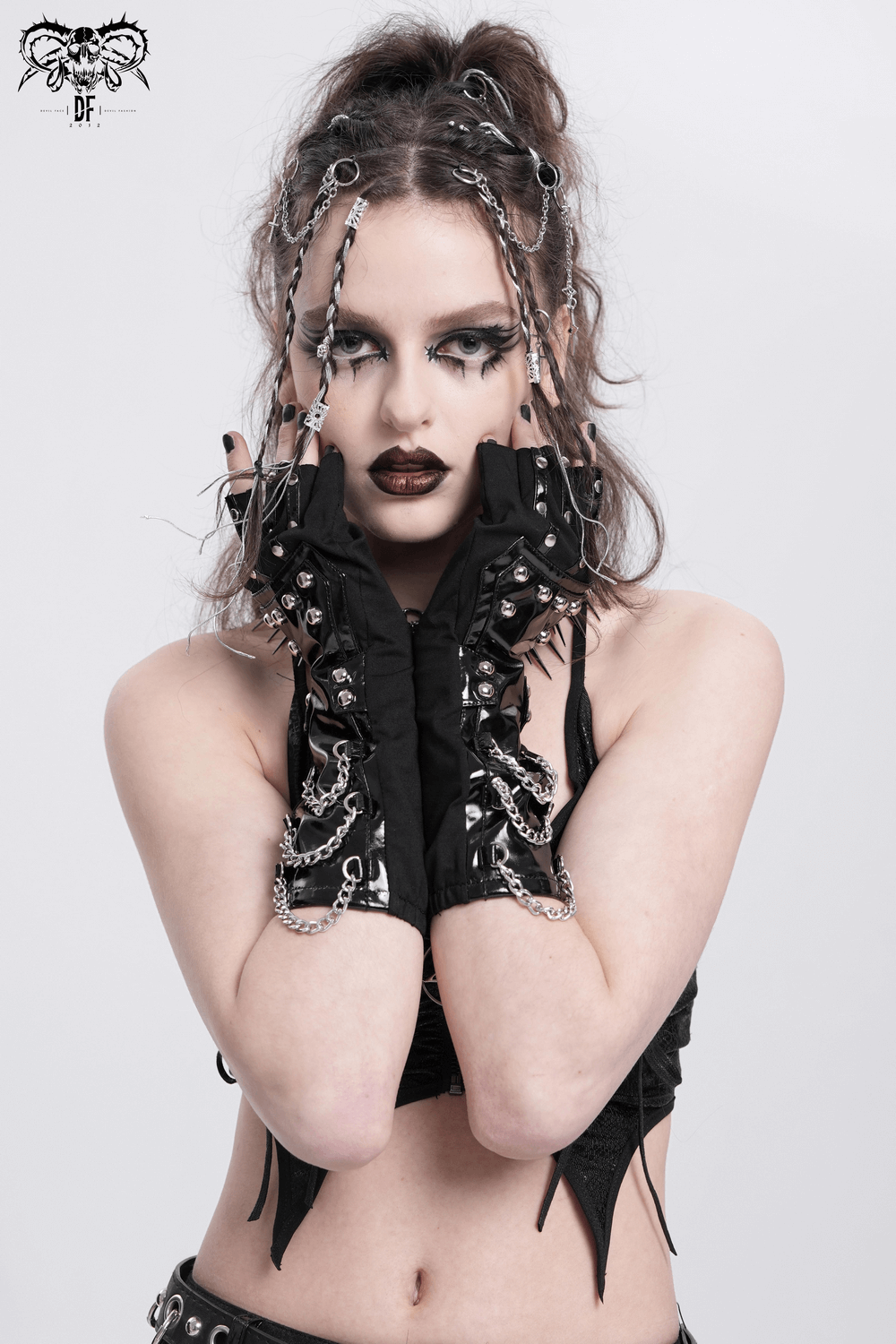 Edgy woman wearing black patent leather gloves with chains and studs, showcasing a daring fashion statement.