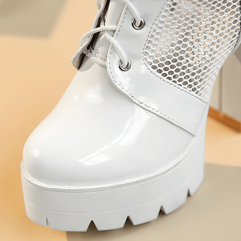 Close-up of white women's patent leather knee-high mesh boot with lace-up detail and chunky heel.