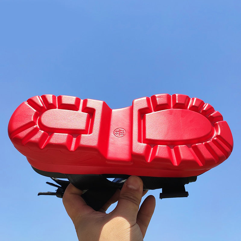Bottom view of red thick-soled platform sandal, showing textured grip and sporty design against a bright blue sky.