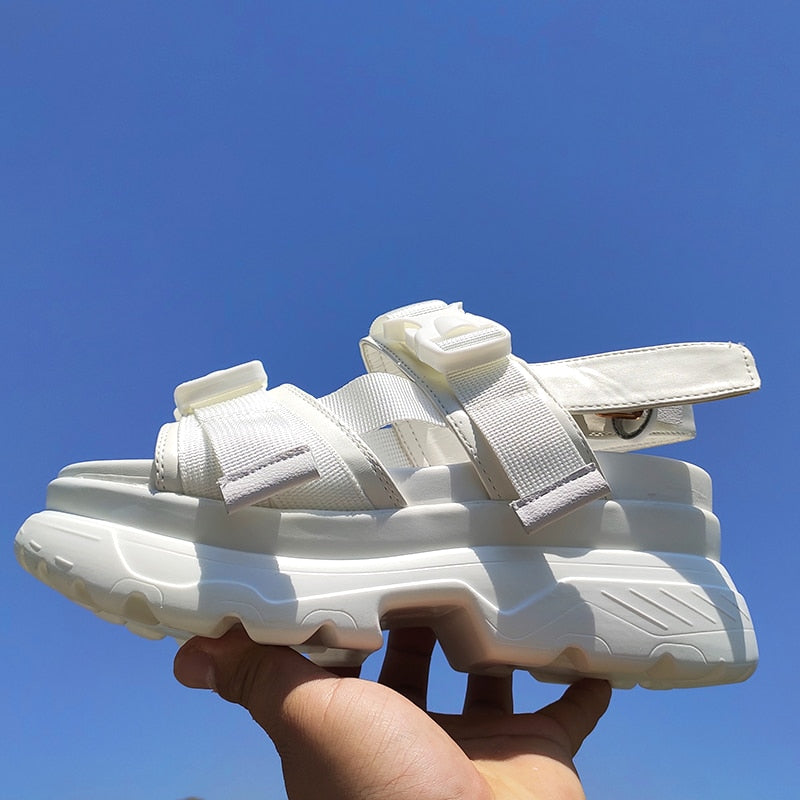 Stylish white women's platform sandals with adjustable straps, perfect for a chic rock look against a clear blue sky.