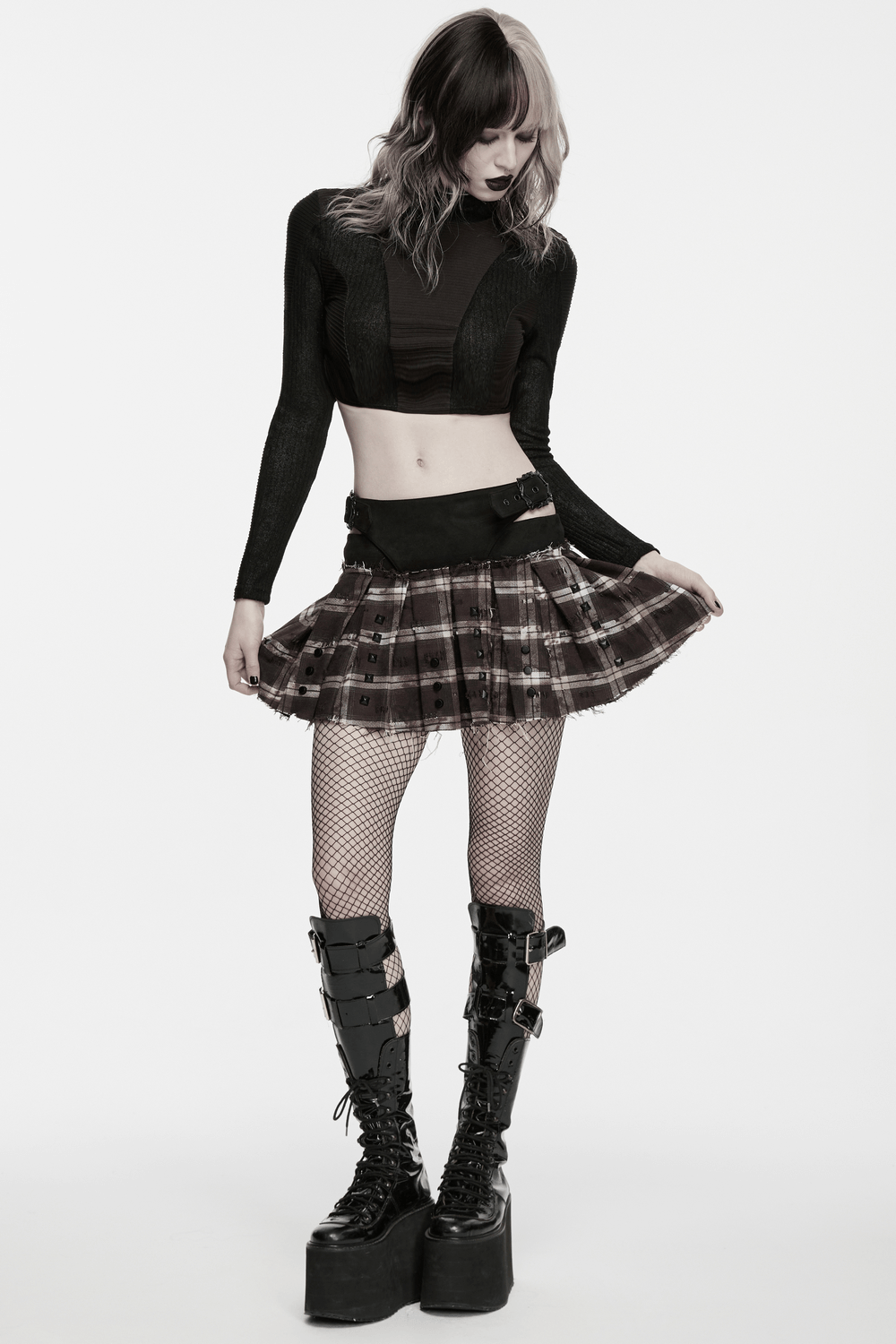 Model wearing a Women's Punk Plaid Mini Skirt with Studded Belt, showcasing edgy street style with fishnet tights and platform boots.