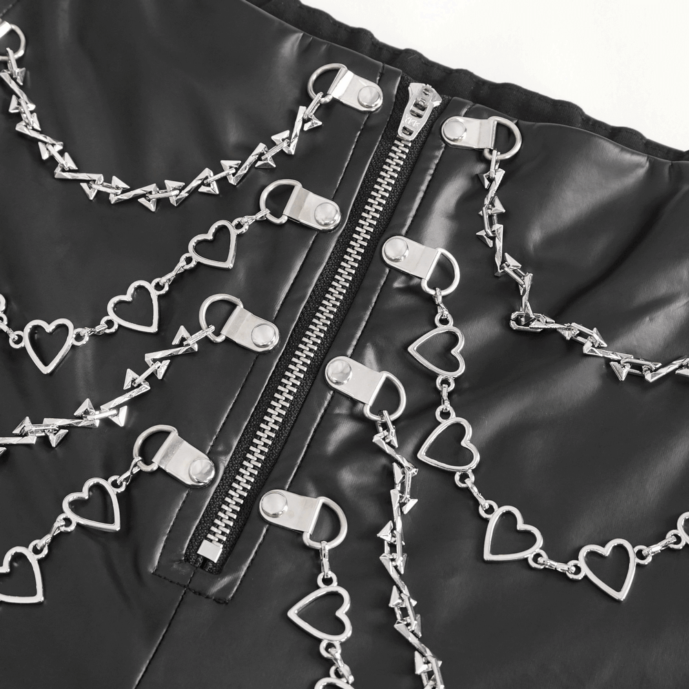 Close-up of women's faux leather pants featuring intricate chain detailing and heart-shaped accents.