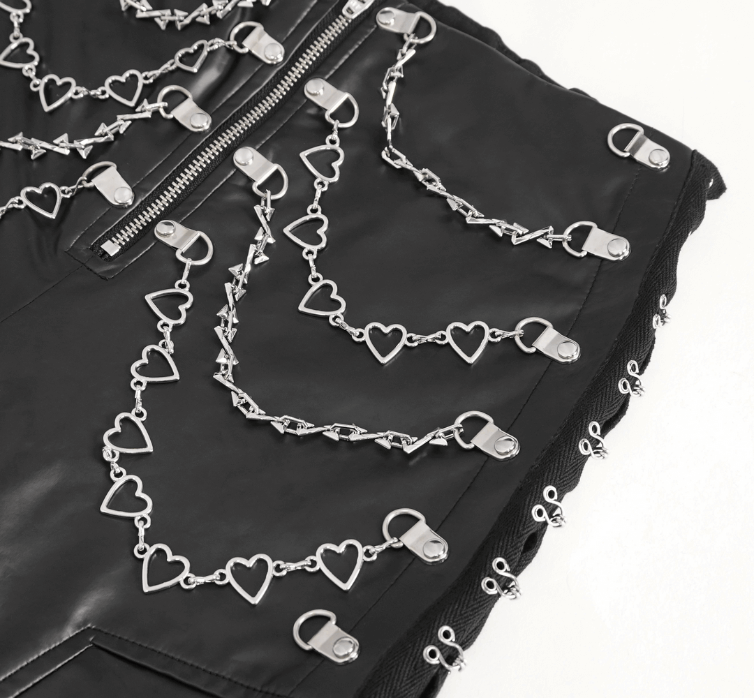 Close-up of sleek black faux leather pants featuring intricate chain and heart detailing for a punk fashion vibe.