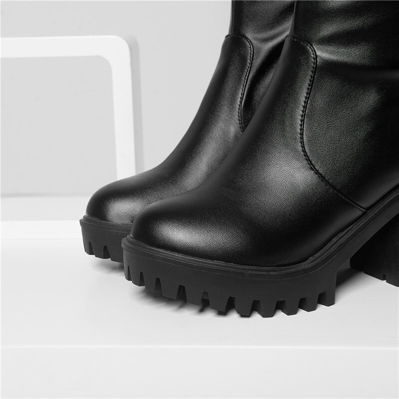 Close-up of women's black round toe platform boots with chunky heels and textured sole, showcasing trendy design.