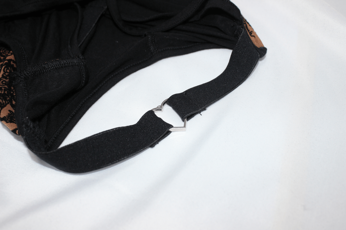 Close-up of a black garment strap with a metal heart-shaped buckle, showcasing elegant gothic design details.