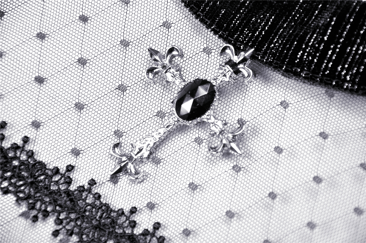 Close-up of vintage-inspired black dress detail featuring sheer fabric and ornate brooch embellishment.