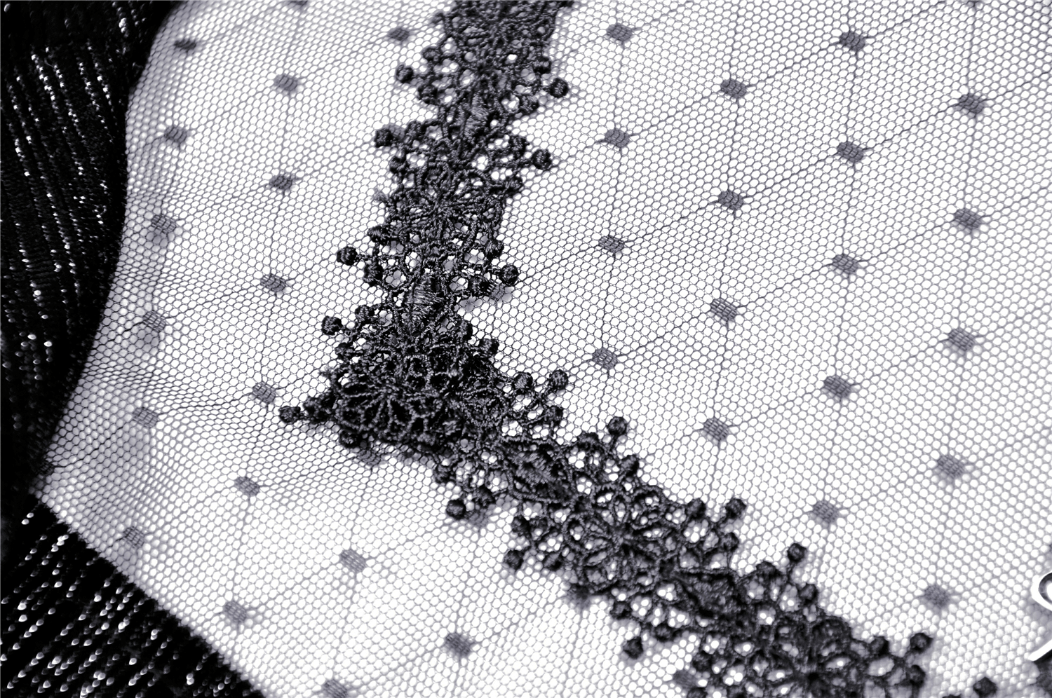 Close-up of sheer black fabric with vintage lace detailing for a stylish look.