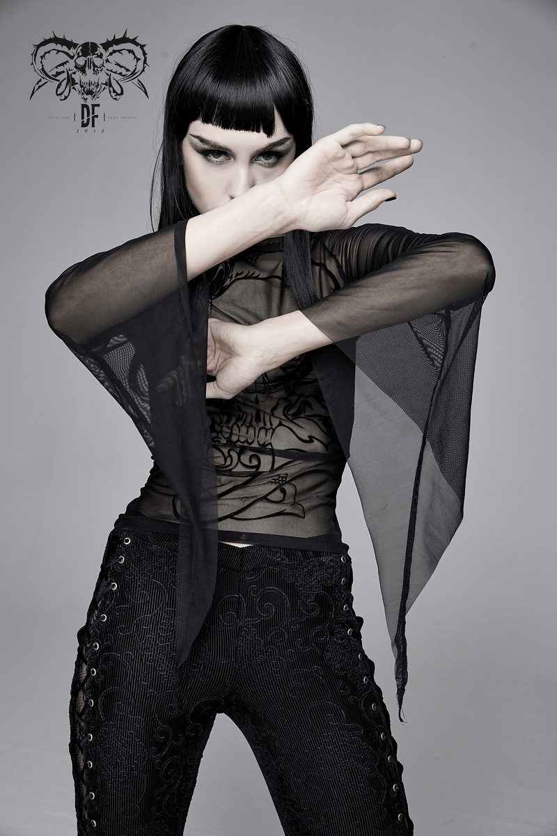 Stylish woman wearing a women's slightly elastic black mesh top with transparent long sleeves and gothic design.