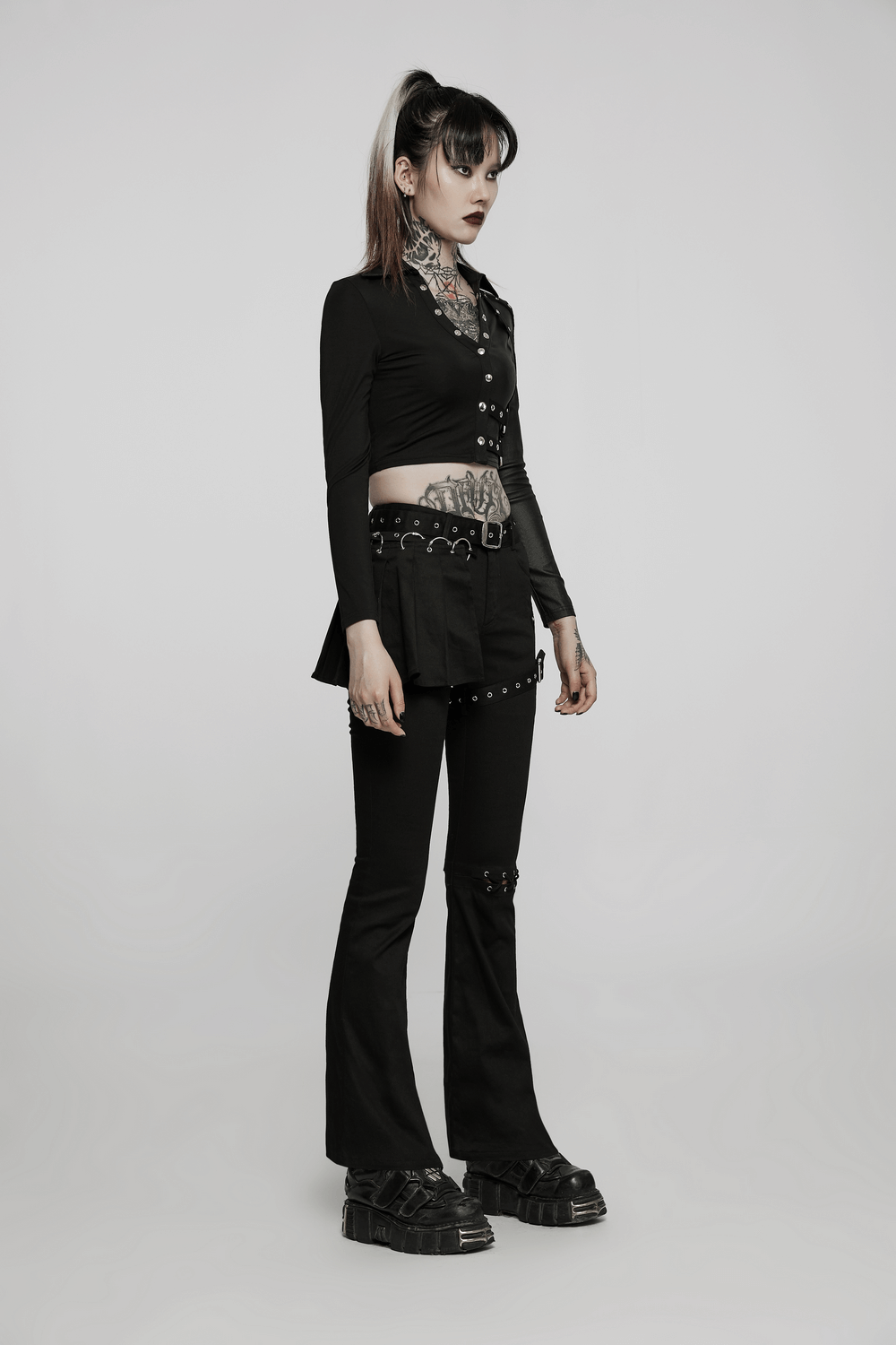 Stylish model in black studded outfit with crop top and flared pants, showcasing a bold, edgy fashion statement.