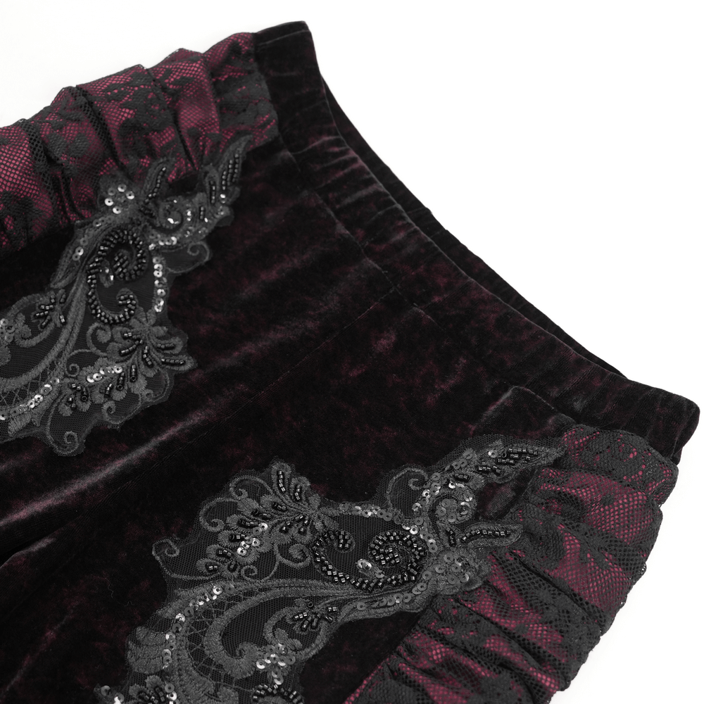 Close-up of women's velvet flare pants with black lace, embroidered appliques, and ruched details, showcasing dark boho style.