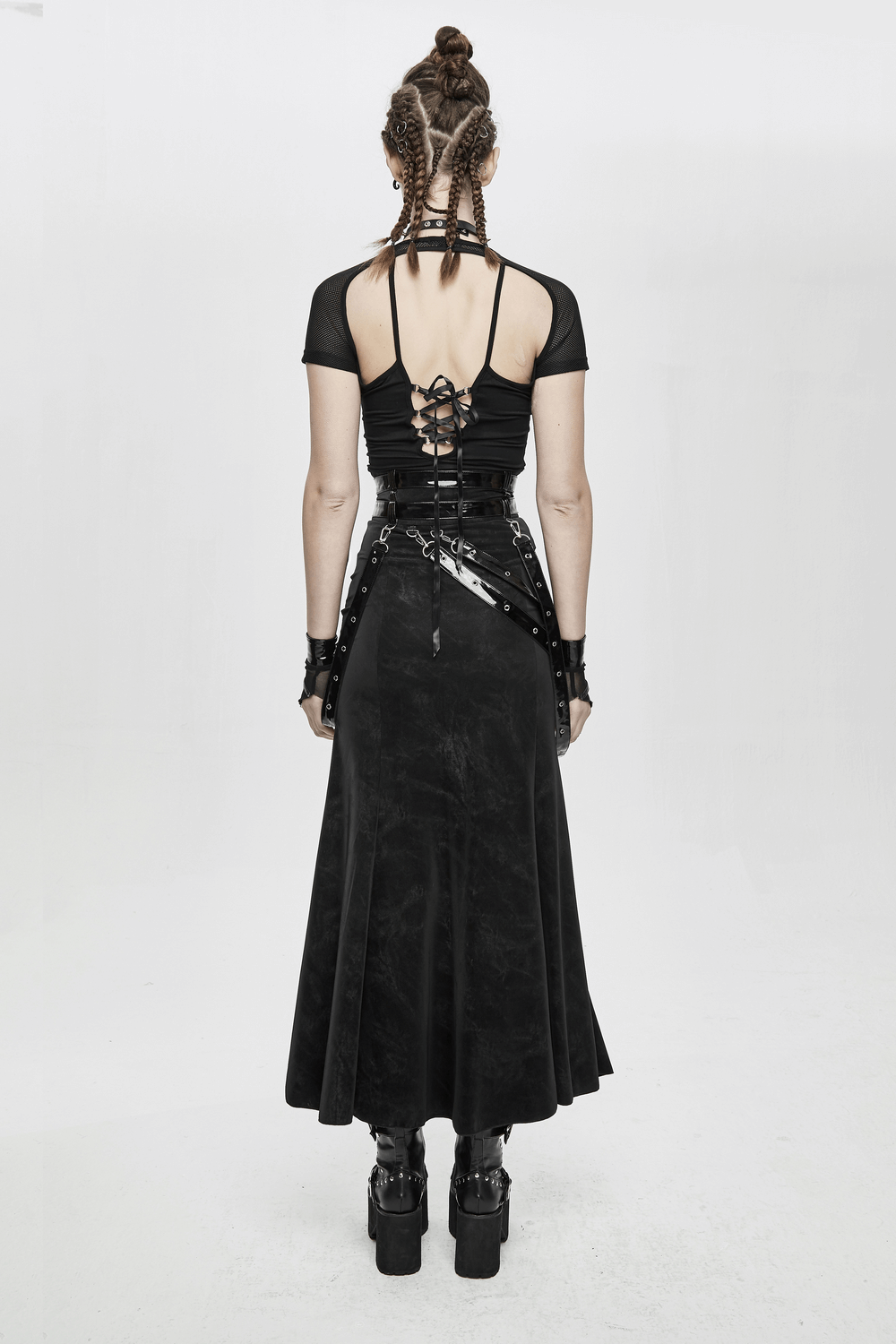 Back view of a model in a black vintage long skirt with straps, rivets, and grunge style accessories, perfect for steampunk fashion.
