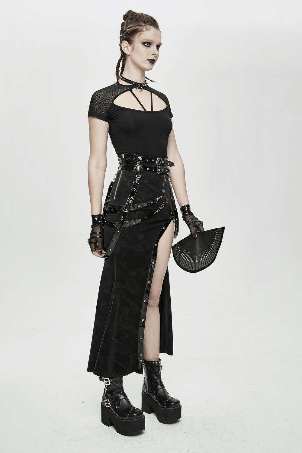 Gothic style woman in black vintage long skirt with straps, rivets, paired with edgy accessories and platform boots.