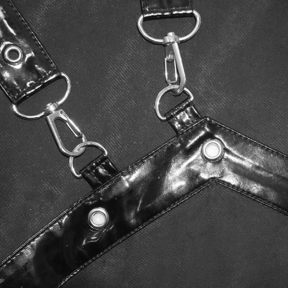 Close-up of black straps with rivets and clips, perfect for steampunk fashion and vintage gothic apparel.