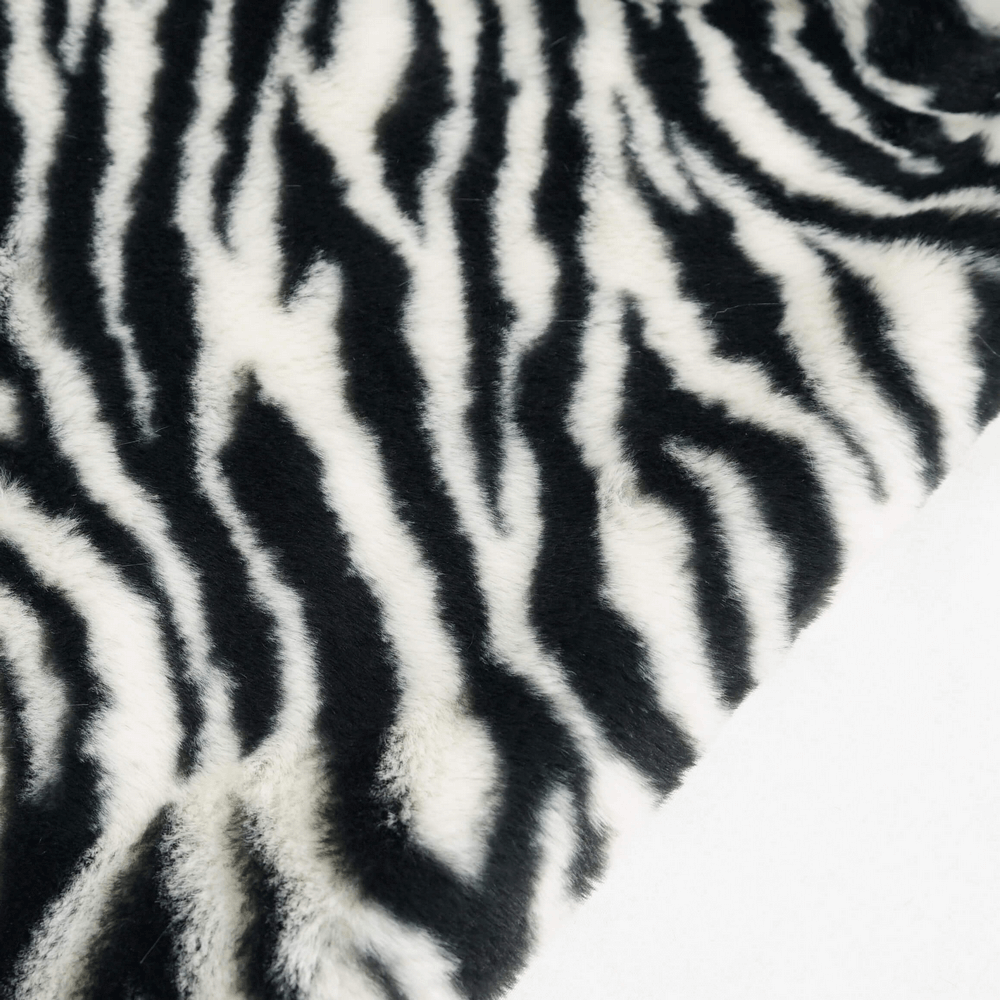 Close-up of stylish zebra-print fabric showcasing bold black and white stripes for fashionable outerwear.