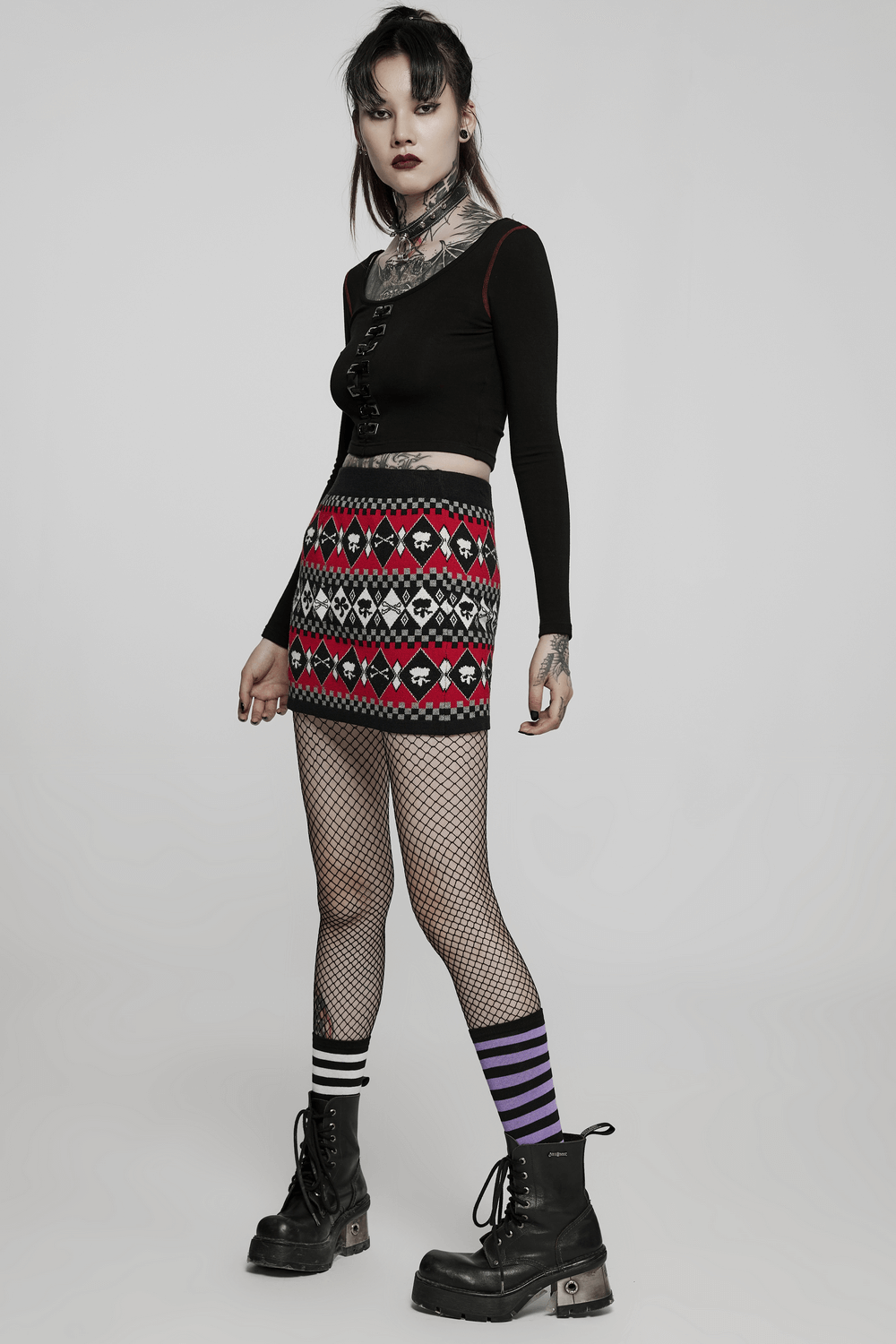 Wool-blend knit skirt with geometric skull pattern, paired with a black top and fishnet stockings, perfect for edgy fashion.