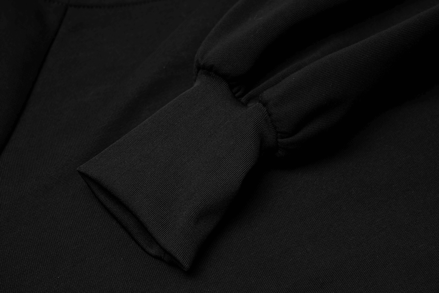 Close-up of black zip-up crop jacket sleeve detail showcasing soft cotton fabric and fitted cuff.