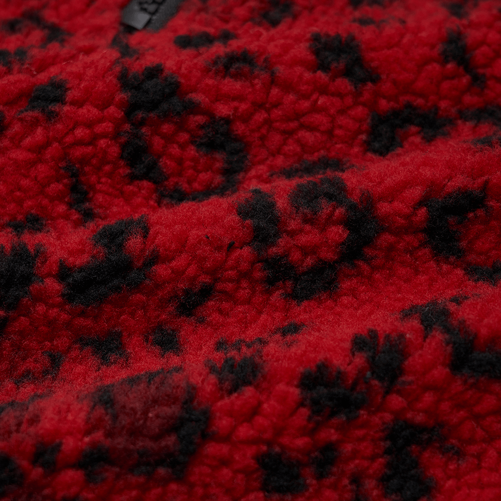 Close-up of red leopard print fleece fabric, showcasing plush texture and bold black spots for a punk mini skirt.