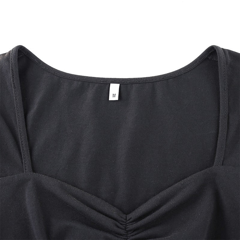 Close-up of the square neck of a women's elegant black dress with size tag 'M' showcasing the quality fabric and design.