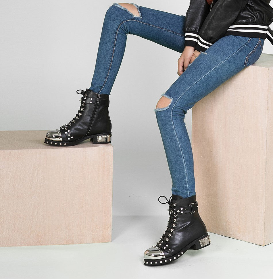 Genuine leather punk rock ankle boots with rivets and square heels, paired with ripped jeans for an edgy look.