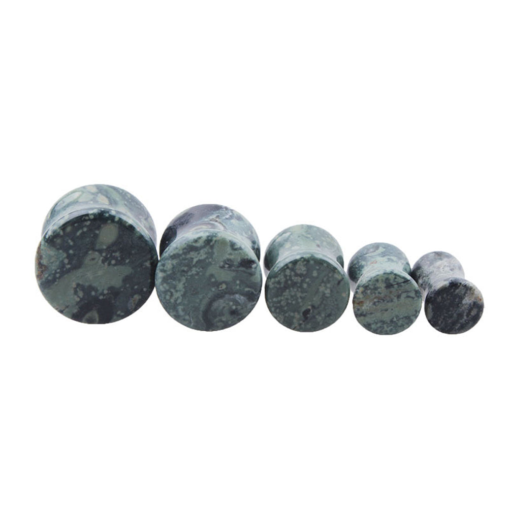 Set of green eye stone ear plugs and gauges, stylish body jewelry for unisex piercing.