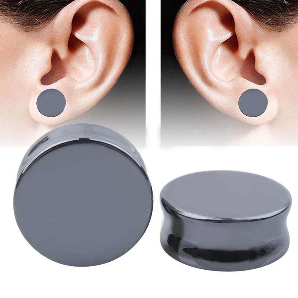 Hematite stone ear plugs sitting next to ears, perfect for stylish body jewelry and trendy piercings.