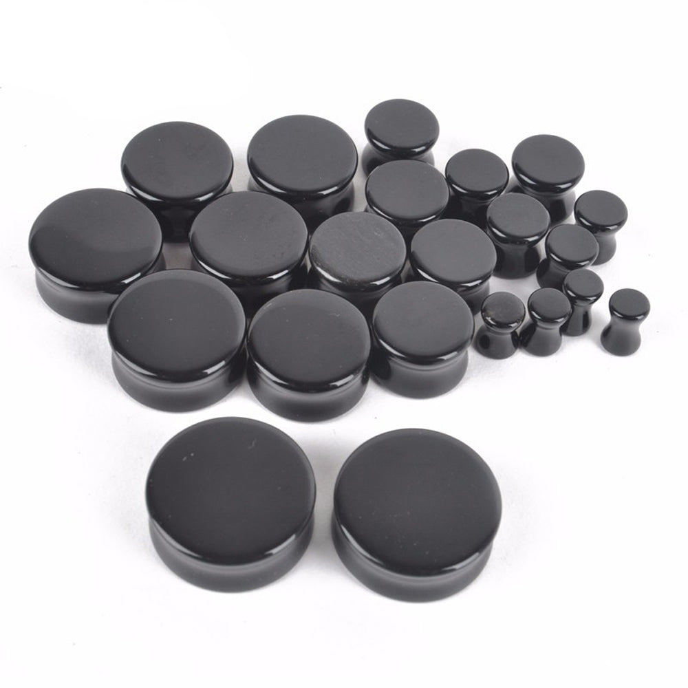 Assorted black obsidian stone ear plugs and gauges displayed together, perfect for body piercing and trendy accessories.